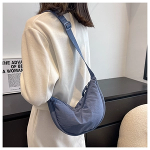 Rear view of a model wearing the blue nylon crescent crossbody bag with adjustable strap