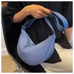 Detailed view of a blue nylon crescent crossbody bag worn by a model in a casual setting
