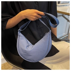 Close-up of a light blue nylon crescent bag with adjustable strap and zip closure
