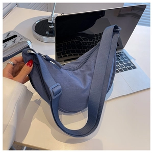 Detail of blue nylon crescent crossbody bag featuring an adjustable strap and smooth texture