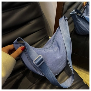 Close-up of a blue nylon crescent bag featuring zipper detail and adjustable strap