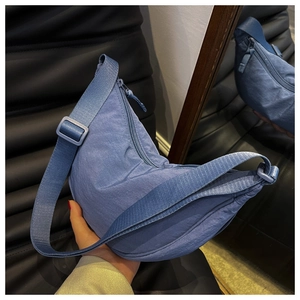 Detailed shot of a blue nylon crescent bag with adjustable strap and zip closure