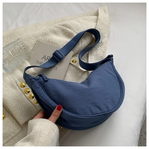 Detail of blue nylon dumpling crossbody bag featuring adjustable strap and smooth zipper