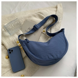 Detailed top view of a blue nylon crescent bag styled with artistic lifestyle props