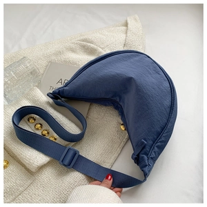 Flat lay of a dark blue nylon crescent crossbody bag with adjustable wide strap