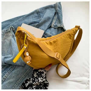 Detail of yellow nylon crescent crossbody bag with a cute duck charm and adjustable strap