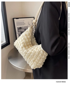 Detail of cream white pleated shoulder bag with popcorn texture and knot strap
