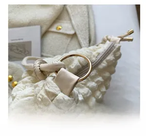 Detail of off-white bubble fabric texture with gold round metal ring and zipper