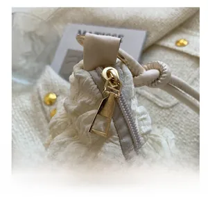 Detailed close-up of smooth gold zipper on beige quilted puff fabric tote bag