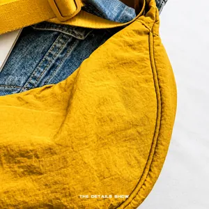 Detalle del bolso de media luna en nailon amarillo brillante con textura suave y costuras