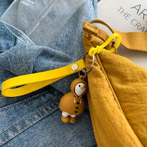 Primer plano de un lindo colgante de pingüino en un bolso bandolera de nailon amarillo vivo