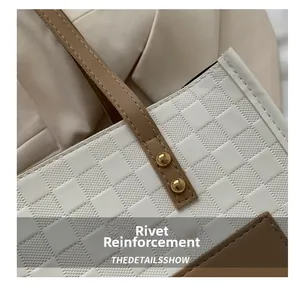 Detail view of white checkerboard pattern tote bag with brown leather strap and gold rivets