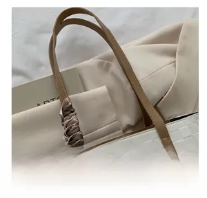 Close-up of checkerboard textured tote bag with leather handle and silk scarf detail