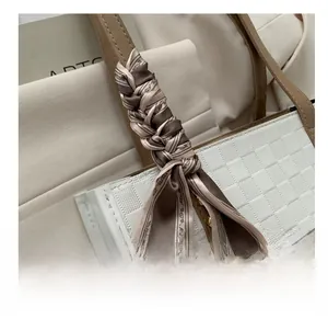 Close-up of geometric pattern scarf wrapped on a leather handle of a beige tote bag