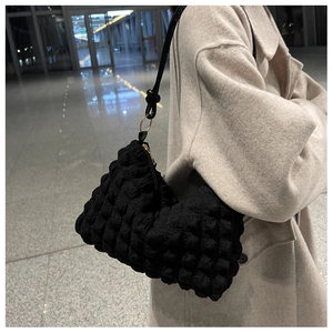 Close-up of black bubble textured fabric on a shoulder bag with slim strap