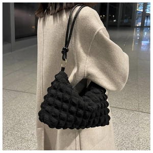 Close-up of black popcorn texture shoulder bag with golden metal ring and slim strap