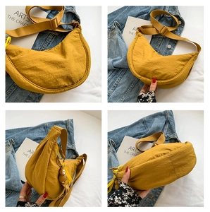Mustard yellow nylon crescent bag with adjustable strap and a brown bear pendant charm