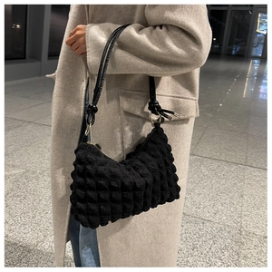 Detail of black bubble texture shoulder bag with knot strap and gold metal hardware