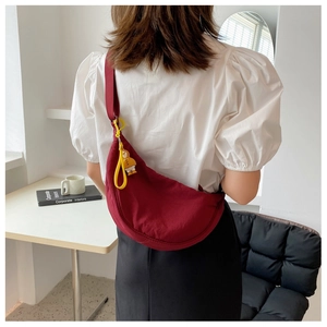Close-up of a dark red nylon crescent bag with a cute yellow duck charm on model