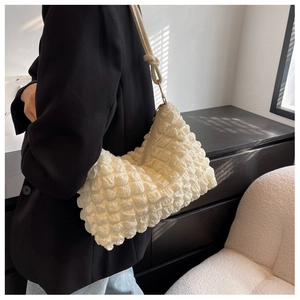 Close-up of soft pleated cream shoulder bag with textured bubble fabric and knotted strap