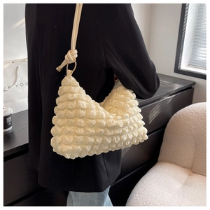 Detail of cream pleated bubble texture shoulder bag with knotted strap and gold hardware