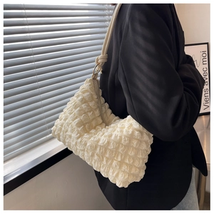 Side view of white popcorn texture shoulder bag on model with elegant light and shadow