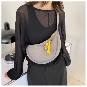 Gray nylon crescent waist bag with yellow zipper detail and cute duck charm on a model