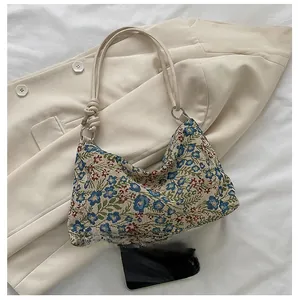 Detailed macro of floral jacquard underarm bag with knot strap and silver ring accents