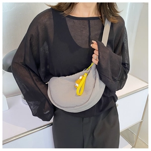 Close-up of a grey nylon crescent-shaped crossbody bag featuring a cute yellow charm