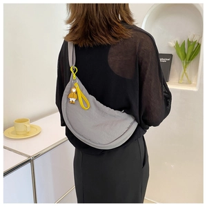 Detail of grey nylon crescent crossbody bag with yellow lanyard and cute charm decoration