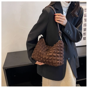 Detailed view of dark brown bubble textured material on a soft shoulder bag with slim strap