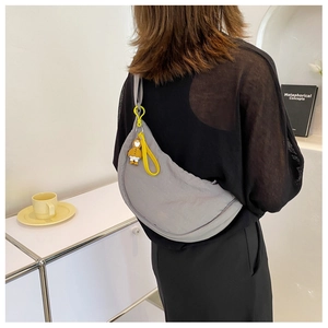 Gray nylon crescent shoulder bag shown with a yellow cartoon charm on a model