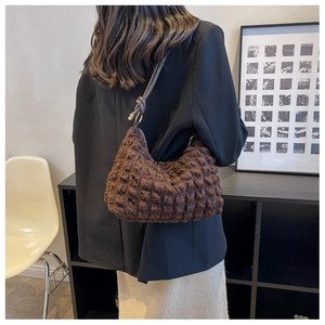 Detail of dark brown bubble cloud bag with soft pleated texture and golden rings