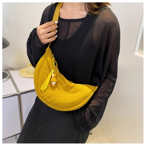 Close-up of bright yellow nylon crescent crossbody bag with cute duck charm on strap