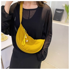 Close-up of bright yellow nylon crescent crossbody bag with animal charm on model