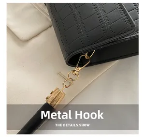 Detail of the golden metal hook and crocodile texture on the black shoulder bag