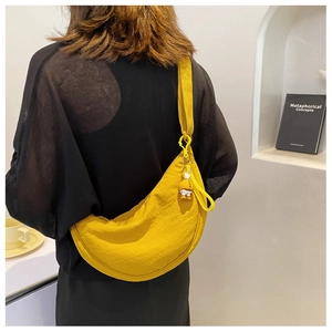 Model view of a bright yellow crescent nylon bag featuring a cute rubber duck pendant accessory