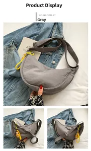 Detail of grey nylon crescent crossbody bag with smooth zipper and yellow cartoon charm