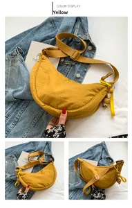 Detail of yellow nylon crescent waist bag with adjustable strap and penguin charm accessory