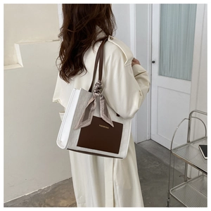 Détail du sac cabas en cuir avec poche contrastée et foulard en soie décoratif sur l'anse