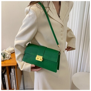 Detail of vivid green crocodile pattern leather bag with gold square buckle closure