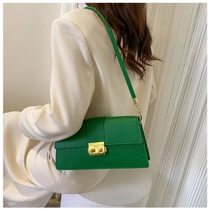 Detail of green faux crocodile skin shoulder bag with gold square metal clasp on a model