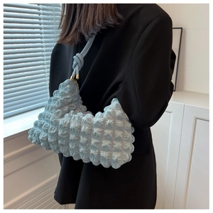 Close-up of sky blue bubble textured shoulder bag with knotted strap and metal zipper