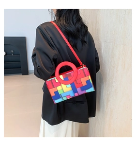 Détail du sac à main bicolore avec poignée ronde rouge et bandoulière en cuir assortie