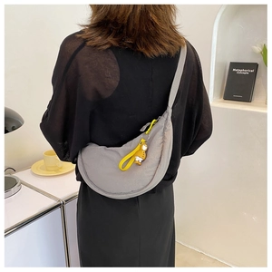 Grey nylon crescent waist bag with yellow zipper accents and decorative pendant charm