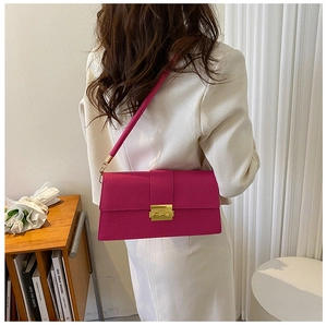 Detail of a bright magenta flap bag with gold buckle and textured leather finish