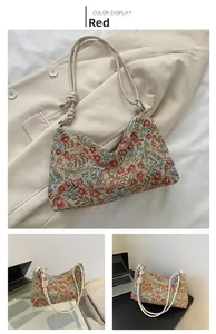 Detail of red floral jacquard underarm bag with decorative rope strap and elegant texture