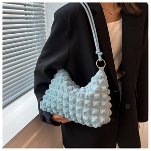 Close-up of light blue bubble textured shoulder bag with knot detail and gold metal ring