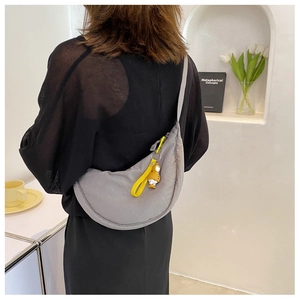 Detail of grey nylon crescent crossbody bag with yellow zipper pull and cartoon charm