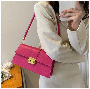 Fuchsia crocodile embossed shoulder bag with gold clasp shown on model with beige blazer